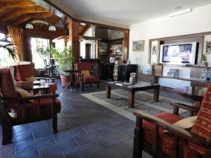 ein Wohnzimmer mit Stühlen, Tischen und einem TV in der Unterkunft Patagonia Queen Hotel Boutique in El Calafate