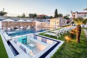 a swimming pool with chairs and tables next to a building at Epicentrum Suites in Limenaria