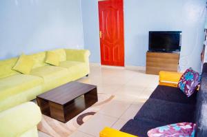 a living room with a yellow couch and a tv at INKINDI Property in Kigali