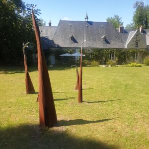 Trois poteaux en bois dans un champ avec une maison dans l'établissement Bed & Breakfast - La closerie de la Fuye, à Ballan-Miré