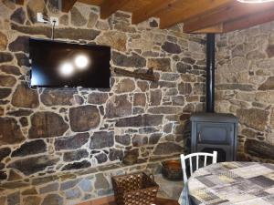 uma parede de pedra com uma televisão e um fogão em A Palleira de Aguil em Castro Caldelas
