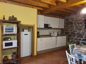 a kitchen with white cabinets and a stone wall at A Palleira de Aguil in Castro Caldelas