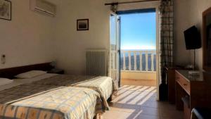 a bedroom with a bed and a balcony with a view at Sariza Spring Hotel in Andros