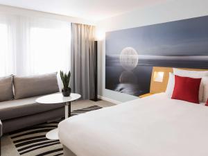 um quarto de hotel com uma cama e um sofá em Novotel Strasbourg Centre Halles em Estrasburgo