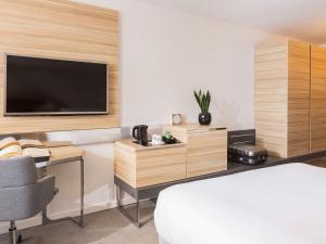 a hotel room with a bed and a desk with a television at Novotel Strasbourg Centre Halles in Strasbourg