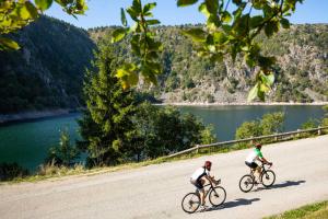 two people riding bikes down a road next to a lake at Le bonhomme proche de Kaysersberg et du lac blanc in Le Bonhomme