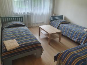 two twin beds with a table in a room at Laukdvaris in Laukžemė