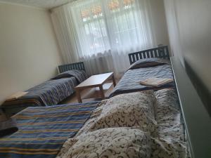 two twin beds in a room with a table at Laukdvaris in Laukžemė