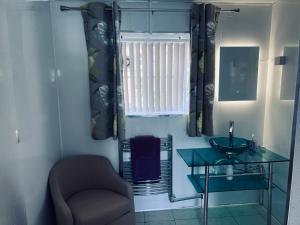 a bathroom with a glass sink and a chair at The Mallards in Sleaford