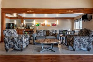 Quality Inn & Suites Warren في Warren: غرفة معيشة مع كرسيين وأريكة وطاولة