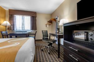Quality Inn & Suites Warren في Warren: غرفه فندقيه بسرير ومكتب وكراسي