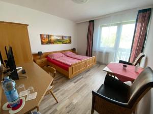 1 dormitorio con cama, escritorio y mesa en Pension Waldschenke am Wörthersee, en Velden am Wörthersee