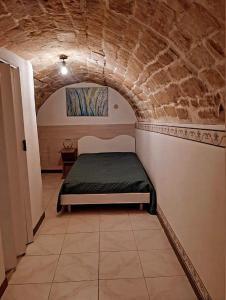 1 dormitorio con 1 cama en una pared de piedra en Le Volte, en Ragusa