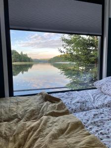 a bed in front of a window with a view of a lake at Półwysep Zacisze - Tiny House Village in Przywidz