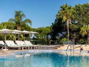 a swimming pool with lounge chairs and umbrellas at Hotel Quinta do Lago in Quinta do Lago