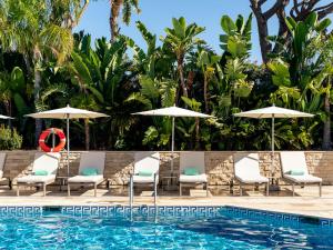 a pool with chaise lounge chairs and umbrellas at Hotel Quinta do Lago in Quinta do Lago