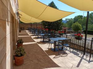 una fila de mesas y sillas bajo una sombrilla en un patio en Hotel Rural Villa de Vinuesa en Vinuesa