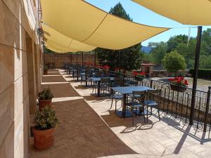 a row of tables and chairs under an umbrella on a patio at Hotel Rural Villa de Vinuesa in Vinuesa