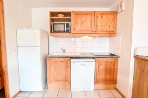 cocina con armarios de madera y nevera blanca en Flat In Residence With Swimming Pool, en Saint-Gervais-les-Bains