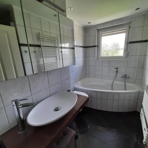 y baño con lavabo, bañera y espejo. en Ferienwohnung Müller, en Duderstadt