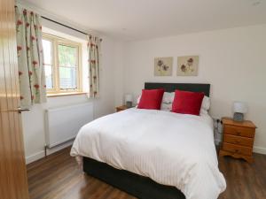 a bedroom with a large white bed with red pillows at Joiners Cottage in York