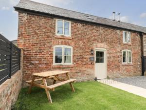 a wooden picnic table in front of a brick building at Spindle Cottage in York