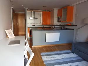 uma cozinha com armários laranja e um sofá azul em Acogedor y tranquilo em Valladolid