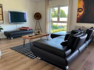 a living room with a black leather couch and a table at Charmante Ferienwohnung 100 qm in Groß-Umstadt