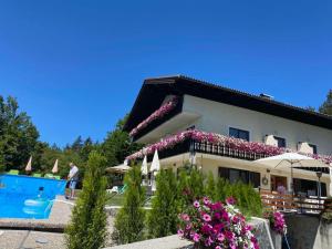 a house with a swimming pool and flowers at Pension Waldschenke am Wörthersee in Velden am Wörthersee