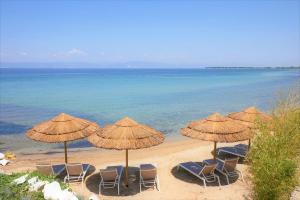 a group of chairs and umbrellas on a beach at Byblos Aqua-The Sea Front Luxury Villa in Skala Sotiros