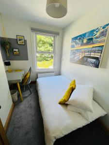 Harbour Cottage في فولكستون: غرفة نوم بسرير ابيض ومخدة صفراء