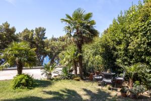 a garden with a table and chairs and palm trees at Sea View & Beach Luxury Palm Garden Split Apartment in Split