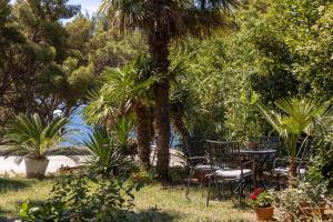 a garden with chairs and a table and a palm tree at Sea View & Beach Luxury Palm Garden Split Apartment in Split