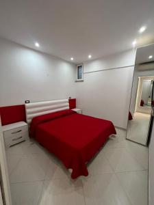 uma cama vermelha num quarto branco com um espelho em Villa Bebe' em Vico Equense
