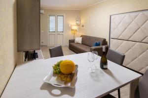 a dining table with a bottle of wine and a plate of fruit at Stella room & apartment in Marsala
