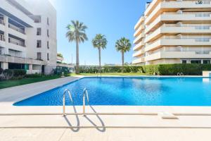 a swimming pool in front of a building with palm trees at Marina Real - Sea View by HD PROPERTIES in Vilamoura
