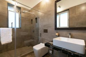 a bathroom with a sink and a toilet and a mirror at Ananda Villa by StayVista - A serene escape with Mountain-view, Heritage interiors, Swimming pool & Lush lawn in Lonavala +24 photos