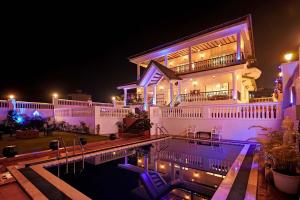 a large house with a swimming pool at night at Ananda Villa by StayVista - A serene escape with Mountain-view, Heritage interiors, Swimming pool & Lush lawn in Lonavala