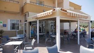 Hotel godisa في Argamasilla de Calatrava: مطعم فيه طاولات وكراسي امام مبنى