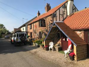 a building with two white chairs outside of it at Yarm Cottages The Byre Sleeping 4 Next to Fox Covert Pub in Kirk Leavington