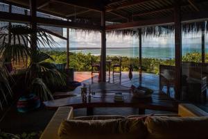 a living room with a table and a view of the ocean at O Céu de Boipeba in Ilha de Boipeba