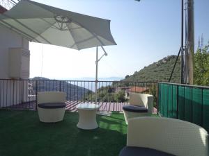 a group of chairs and an umbrella on a balcony at Casa Vacanza Puntaferano in Vico Equense