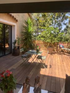 un patio con mesa y sillas en una terraza de madera en Villa de charme avec piscine et jacuzzi dans cadre exceptionnel proche Marseille, en Les-Pennes-Mirabeau