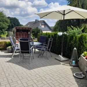 a patio with a table and chairs and an umbrella at Ferienwohnung Heimathafen Westensee in Westensee
