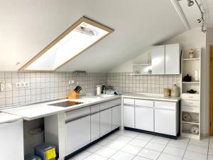 a kitchen with white cabinets and a skylight at Möblierte 3 Zimmer Apartment - Mit Smart TV, Wlan und kostenfreie Parkplätze in Schloß Holte-Stukenbrock