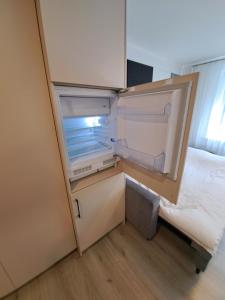 an empty refrigerator with its door open next to a bed at New cosy Karklu Apartment in Klaipeda in Klaipėda