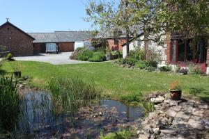 a garden with a pond in front of a house at Beautiful Barn Conversion, 3 Bed, hot tub, sauna, gym, enclosed garden in Ryde