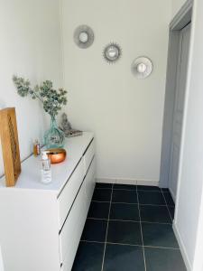 a white bathroom with a vase on a dresser at Maisonnette indépendante au calme in Vittel