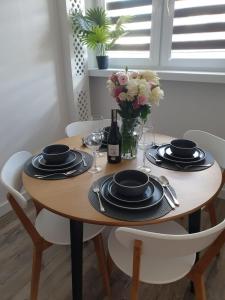 una mesa de madera con platos y un jarrón de flores en Apartament Barcelona, en Kielce 18 fotos más