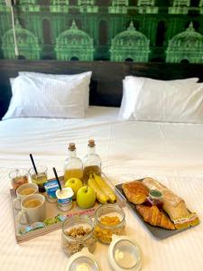 a tray of food and fruit on a bed at Hôtel Une Chambre en Ville in Toulouse